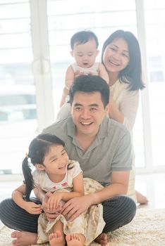 Chinese parents and children piggy back. Happy Asian family spending quality time at home, natural living lifestyle indoors.