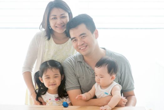 Attractive parents and children portrait. Happy Asian family spending quality time at home, natural living lifestyle indoors.