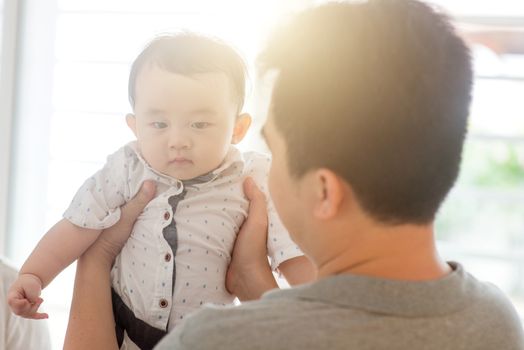 Asian family at home. Father holding child, living lifestyle indoors. 