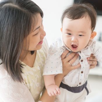 Mother playing with 9 months old baby. Asian family at home, living lifestyle indoors.