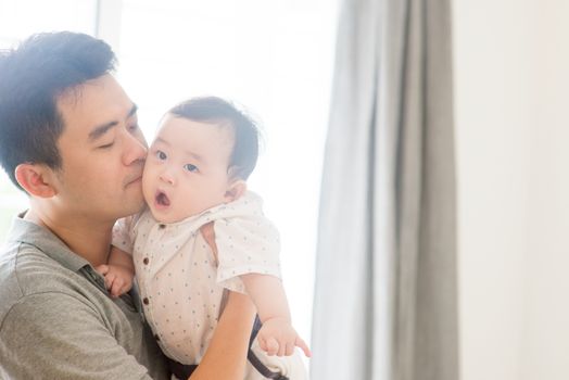 Happy Asian family at home. Father kissing son, living lifestyle indoors. 
