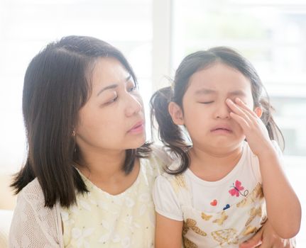 Mother comforting crying child. Asian family at home, living lifestyle indoors.