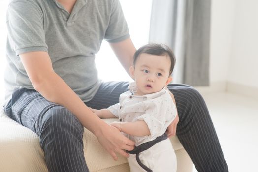 Happy Asian family at home. Father babysitting son, living lifestyle indoors. 