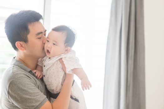 Happy Asian family at home. Father kissing child, living lifestyle indoors. 