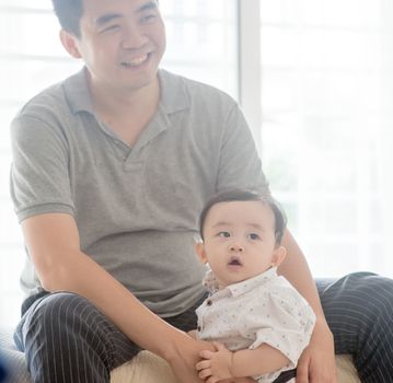 Happy Asian family at home. Father babysitting child, living lifestyle indoors. 