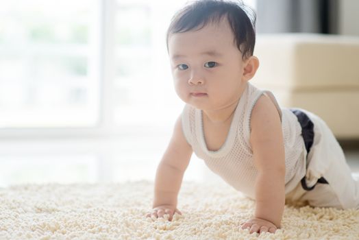 Chinese baby boy crawling on floor. Asian family at home, living lifestyle indoors.