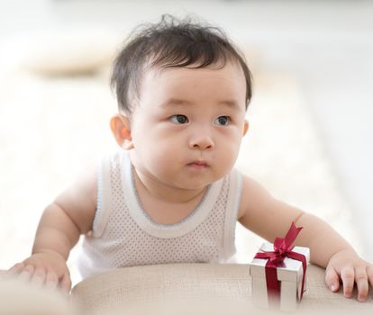 Nine months old baby boy holding sofa learning to walk. Asian family at home, living lifestyle indoors.