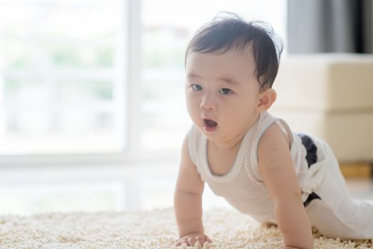 Baby boy crawling on carpet. Asian family at home, living lifestyle indoors.
