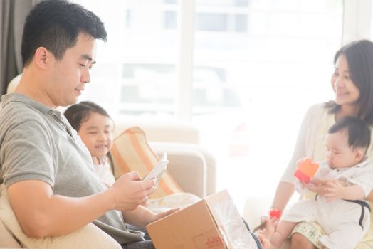 Chinese people scanning QR code with smart phone. Happy Asian family at home, natural living lifestyle indoors.