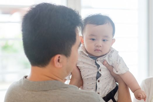 Asian family at home. Father carrying child, living lifestyle indoors. 