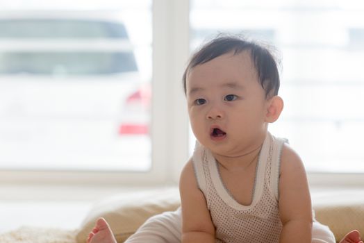 Nine months old baby boy sitting on floor. Asian family at home, living lifestyle indoors.