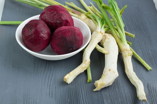 Still life of prepared cleaned raw vegetables beetroot and horseredish for borsch beet soup of russian cuisine on grey wooden background