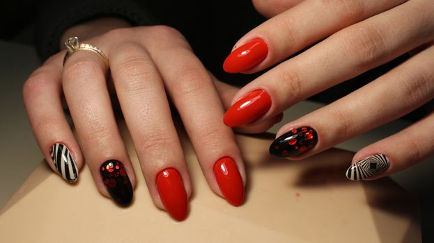 Manicure, design red with black and white geometric abstraction on nails