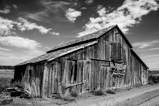 Weathered barn in the Panhandle region of Idaho in black and white with puffy clouds