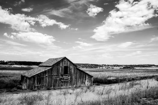 Weathered barn in the Panhandle region of Idaho in black and white with puffy clouds