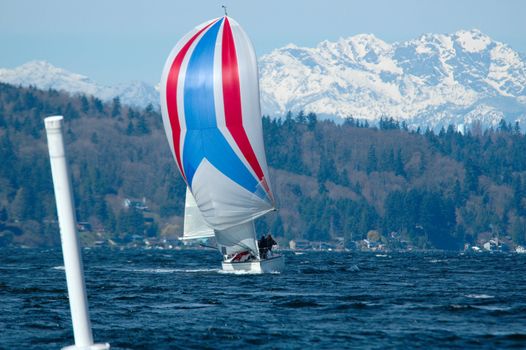 Single boat coming into leeward marke under spinnaker with Olympic Mountains in background.