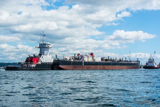 Tug inserted in notch in stern of barge with assist from separate tug.