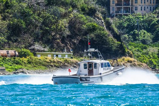 Pilot boat heading out from harbor at high speed with spray in British Virgin Islands