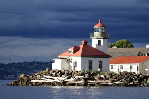 High contrast image of Seattle's Alki Point Lighthouse taken from the water on a cloudy, sunlit day