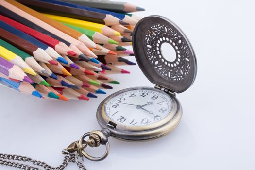 Retro style classic pocket watch and color pencils on white background