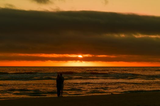 Couple enjoying a romantic sunset at Cannon Beach, Oregon.