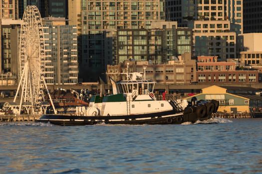 Sunset rsetting on buildings of Seattle with Foss tug, Delta Lyndsey in Elliott Bay.