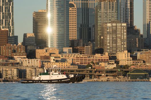 Sunset reflecting off buildings of Seattle with tug in Elliott Bay.