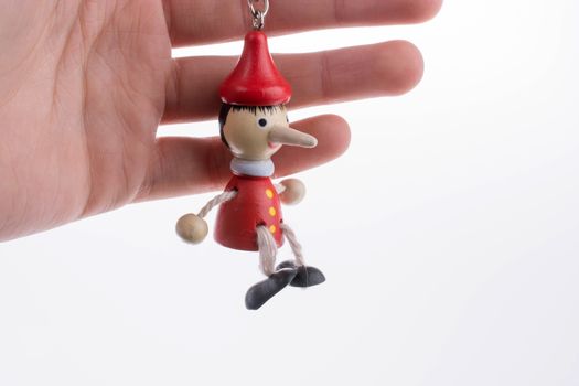 Wooden pinocchio doll with his long nose on a white background