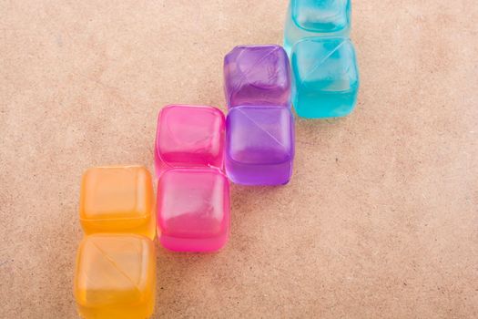 Fake colorful ice cubes on a brown background