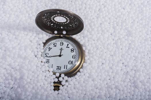 Retro pocket watch on white polystyrene balls