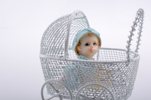 Little baby doll in baby  carriage on a white background