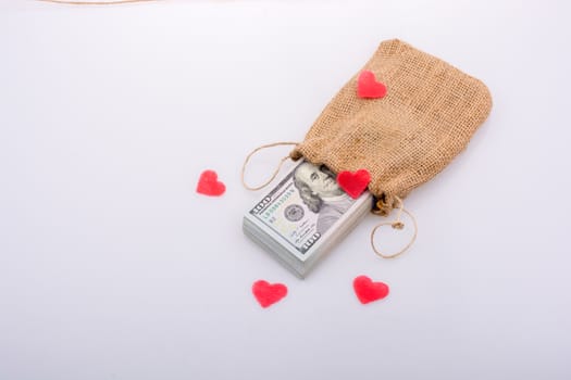 Red hearts and banknote bundle of US dollarin a sack
