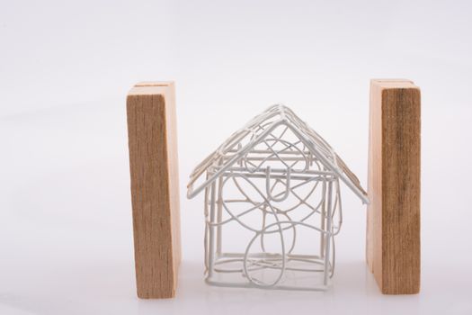 Little metal house  between two domino pieces  on a light  brown color background