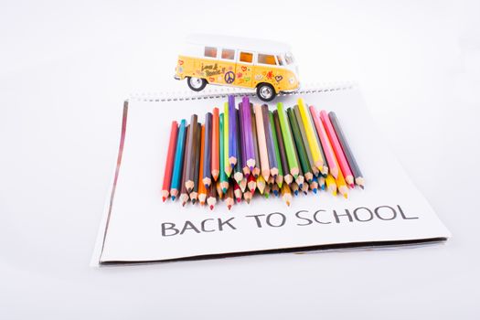 Color pencils, van and back to school title on a notebook