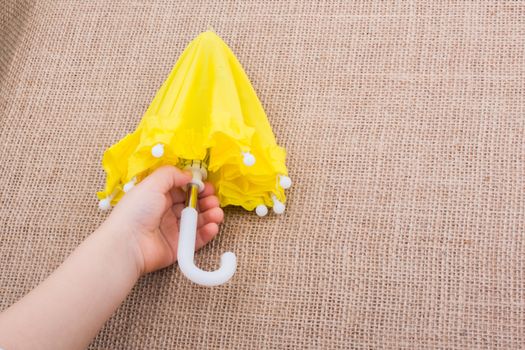 Yellow umbrella in a toddlers hand on canvas