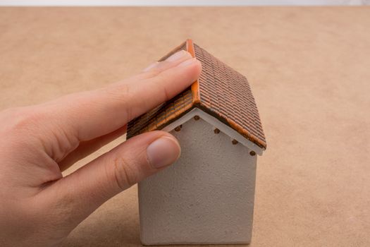 Model house and  a hand on a light  brown color background