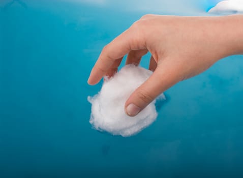 Hand holding some cotton in blue water