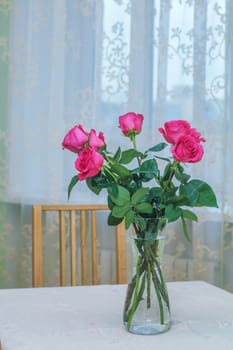 Seven pink roses bouquet in vase standing on table