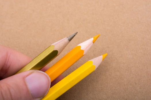 Hand holding color Pencils placed on a brown background