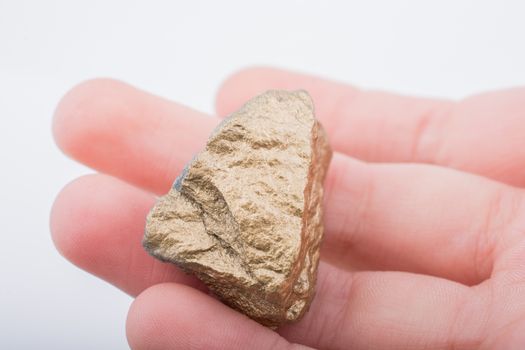 Hand holding a little gold color stone in hand