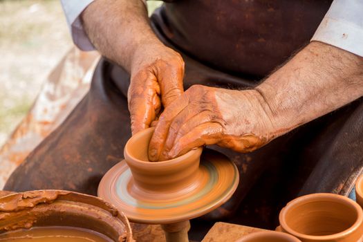 Potter`s hands shaping up the clay of the pot