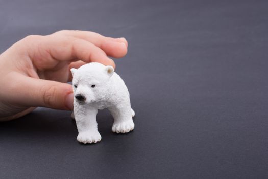 Hand holding a Polar bear model on a dark background