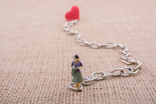 Heart shaped object attached to a woman figurine on canvas