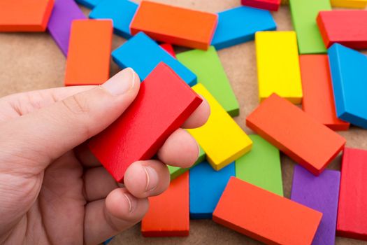 Hand holding one of the wooden blocks of various colors