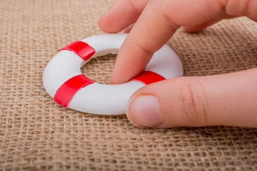 Hand holding a Lifesaver  or life preserver on a fabric background