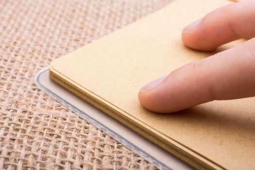 brown color notebook in hand on a canvas background