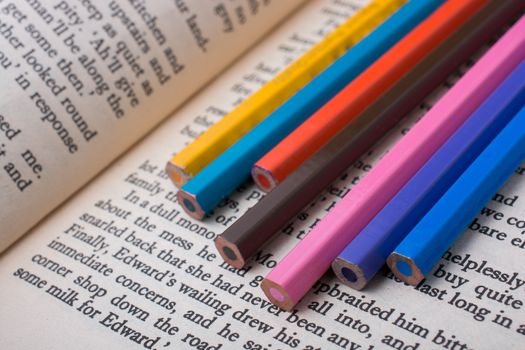 Color pencils placed on the page of a book with text