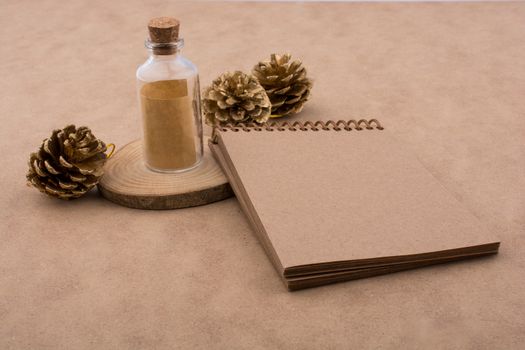 Pine cones, notebook and a bottle on  a piece of cut wood