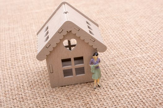 Woman figurine by the side of a model house