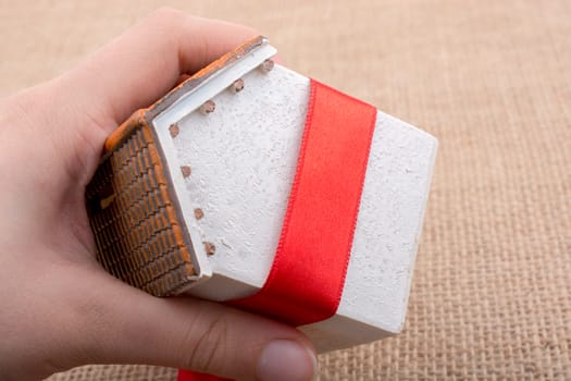 Little model house wrapped in red ribbon on a canvas